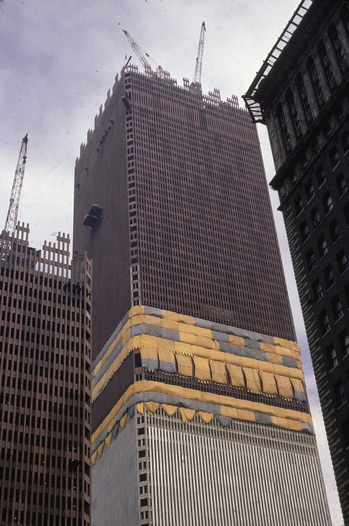 Low-angle view of cranes atop one tower of the World Trade Center during construction, 1970.