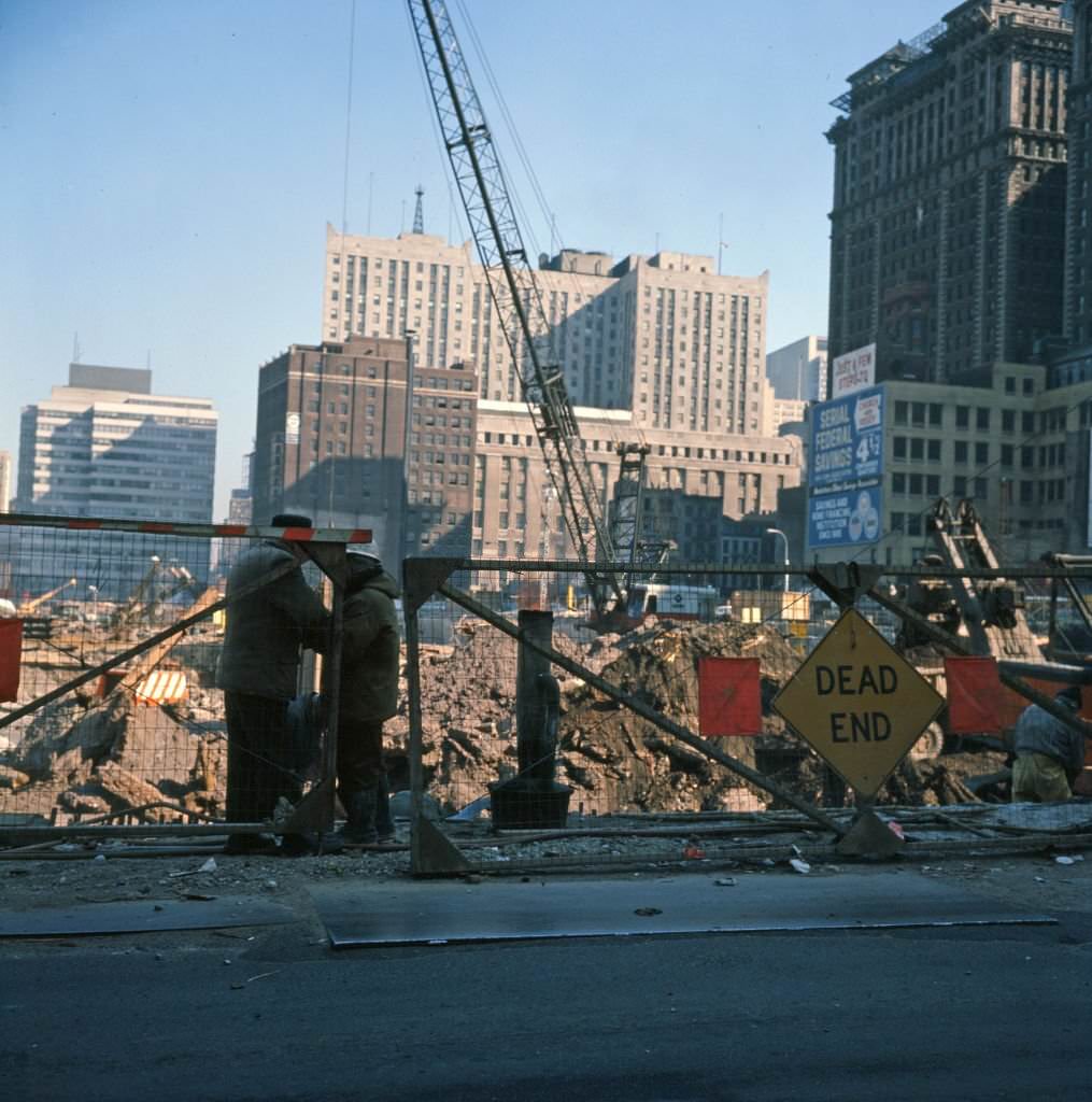 View of two men in front of the construction site for the World Trade Center complex, 1968.