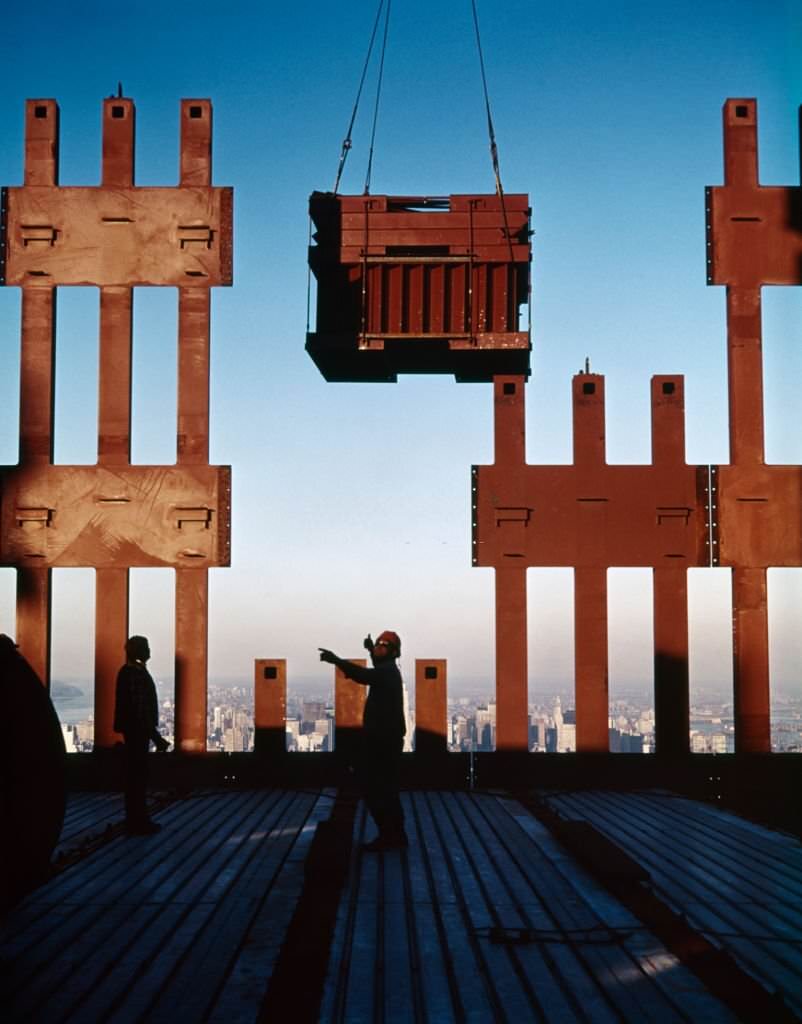 World Trade Center under construction with a worker directing delivery from a crane, 1970s.