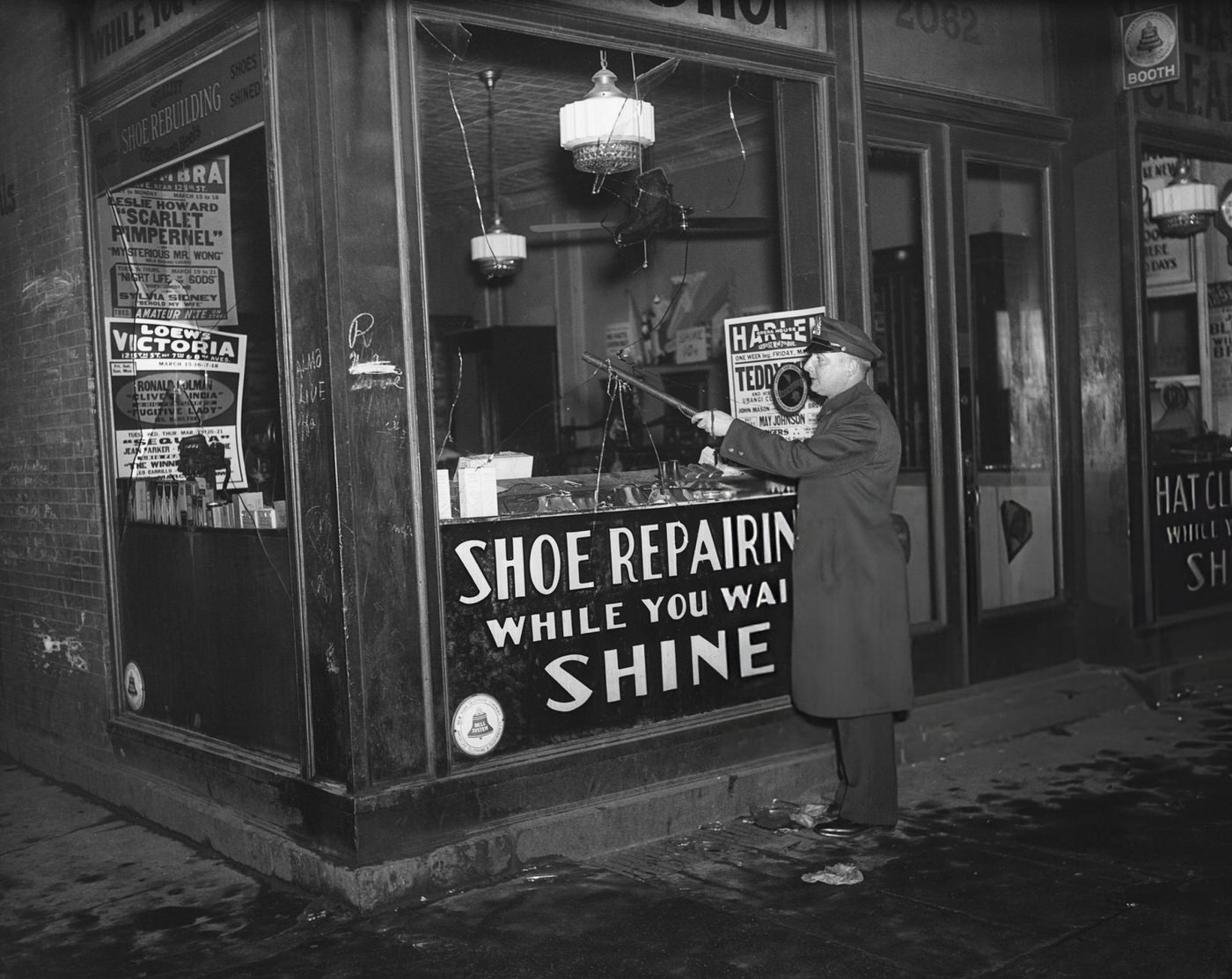 Police Officer Putting His Club Through The Broken Window Of A Shoe Store After Riots In Harlem, 1935.
