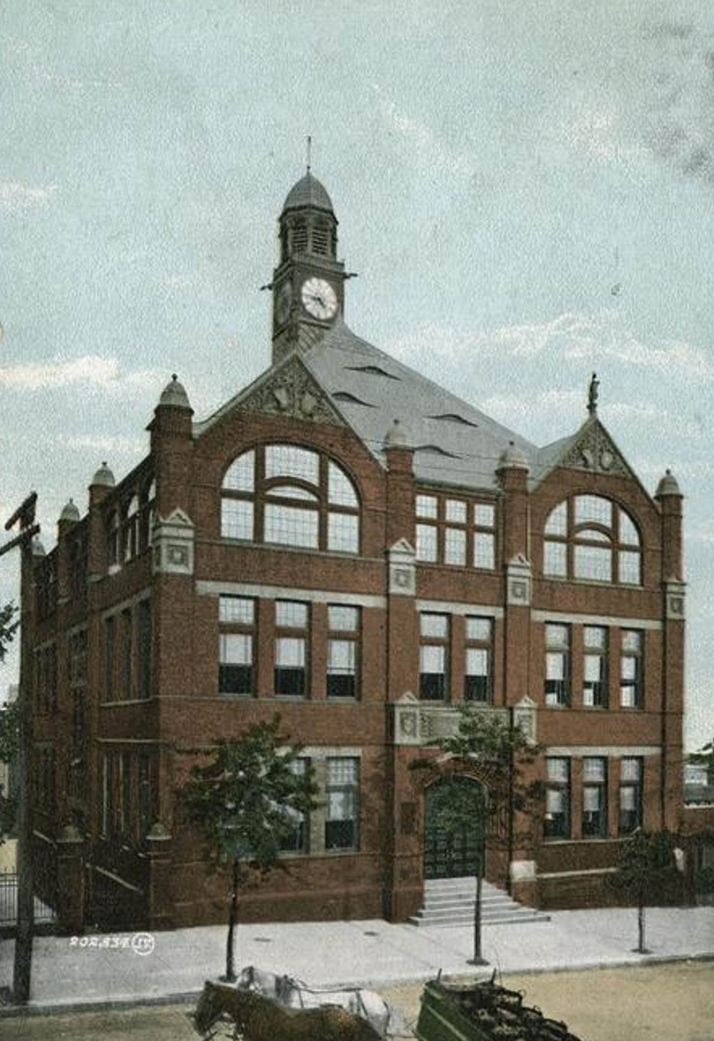 Public School No. 16, Tompkinsville, Staten Island, New York, with horses pulling a freight wagon containing barrels in the street.