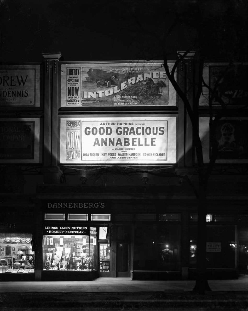 Night View Of Illuminated Storefront Of Dannenberg'S Notions Shop And Billboards For Films, Ca. 1916.