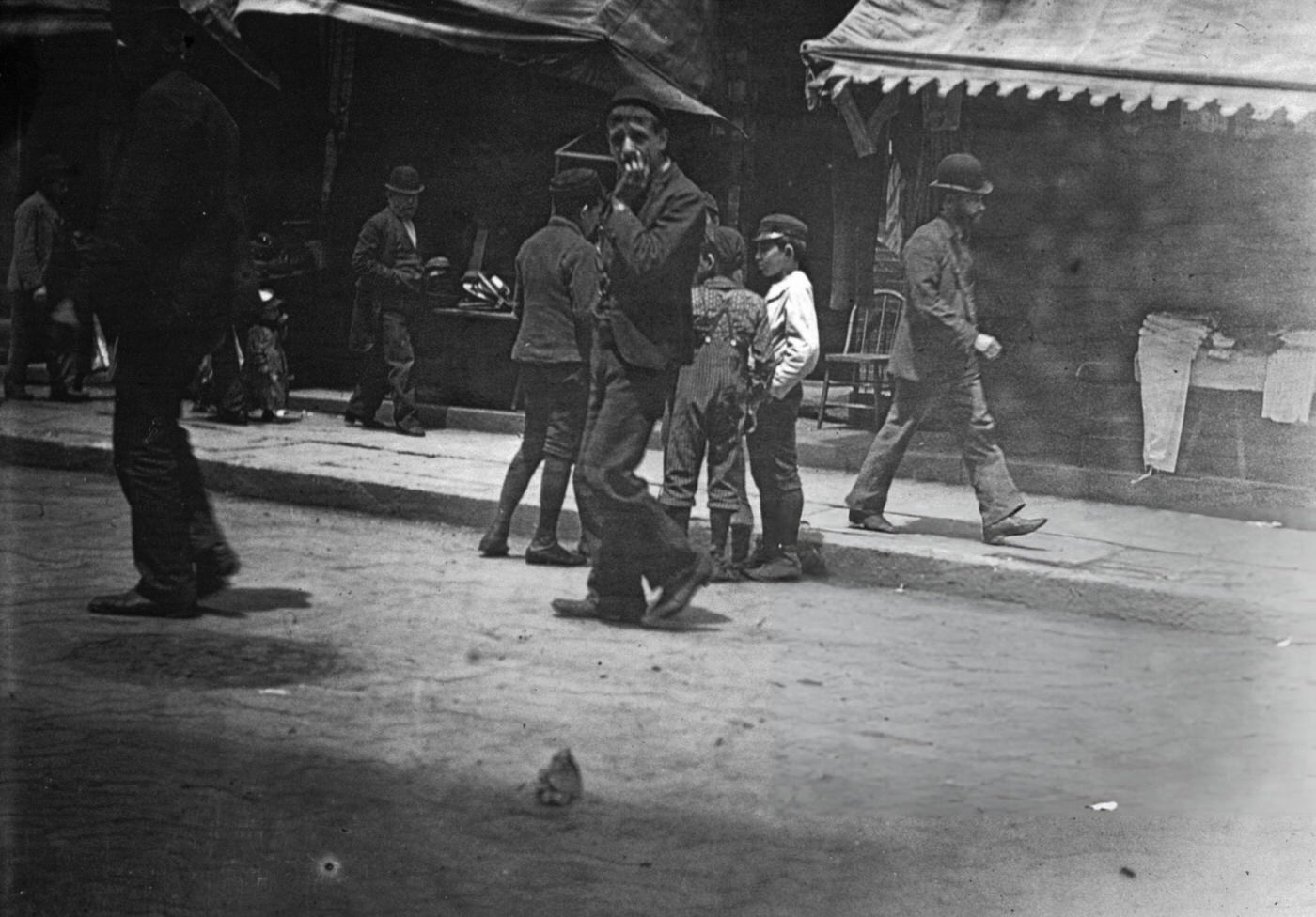 Men Walking Along The Sidewalks And Children Standing In Hester Street On The Lower East Side, 1900.