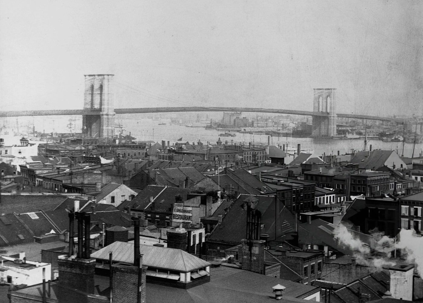 The Brooklyn Bridge Stands Above The Rooftops Of Apartment Houses And Businesses On Manhattan'S Lower East Side, 1900.