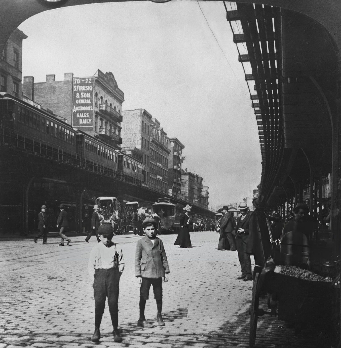 Two Young Boys On A Cobbled Road Beneath An Elevated Rail Line In The Bowery, 1900.
