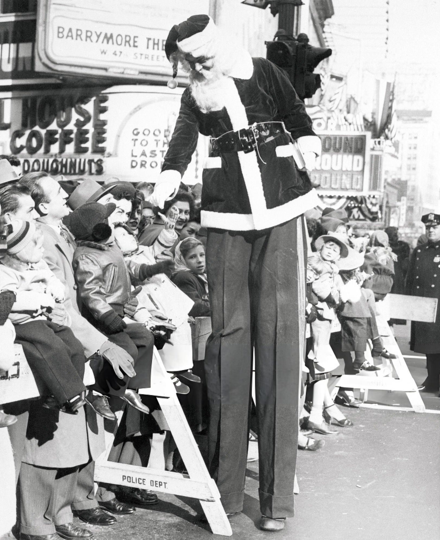 A Santa Claus On Stilts Shakes Hands With Children In Times Square During The Annual Macy'S Thanksgiving Parade.