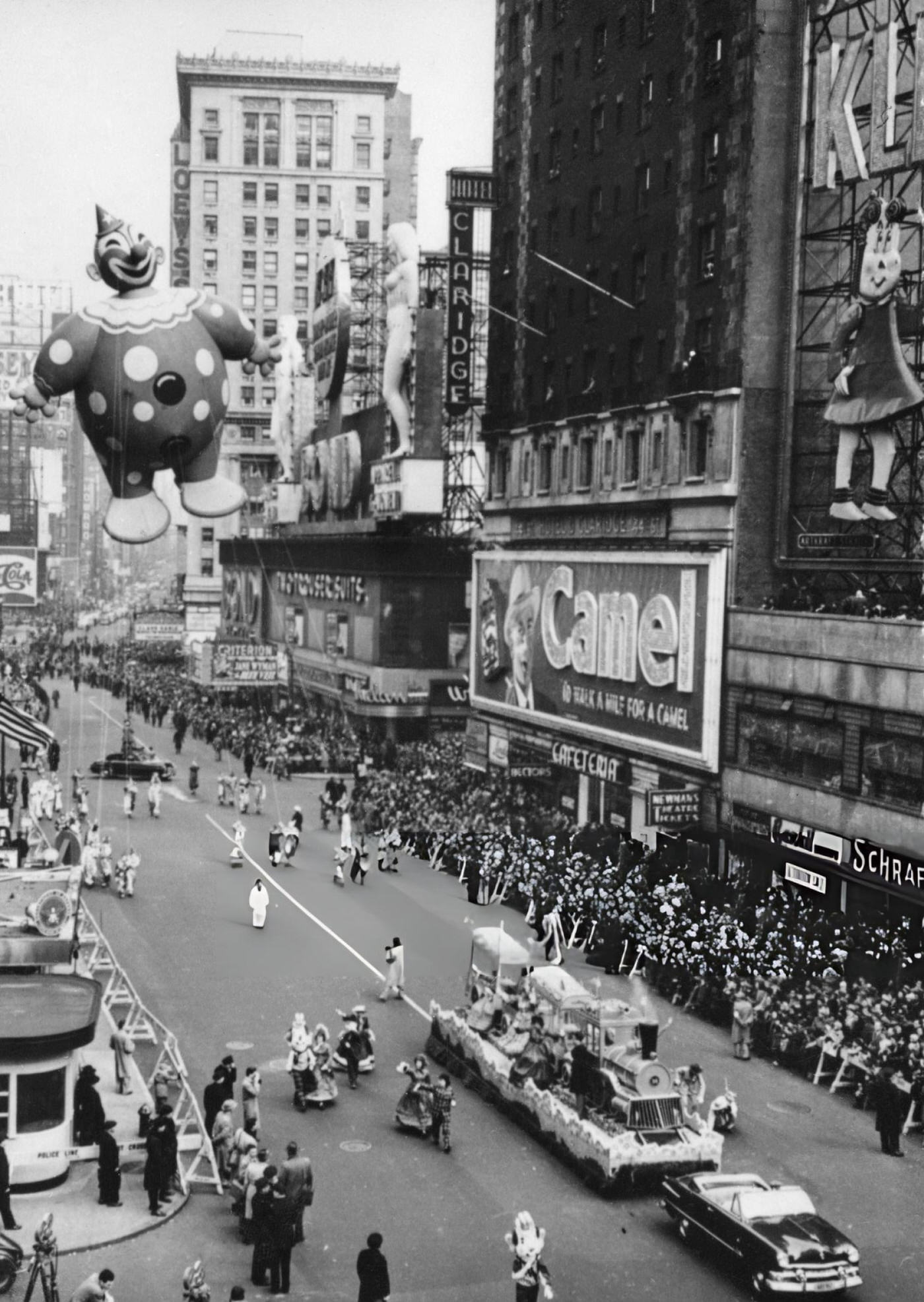 A High-Angle View Of Crowds Watching Macy'S Thanksgiving Day Parade, Featuring A Large Inflatable Clown And A Float With A Locomotive, Passing Through Times Square, 1951.