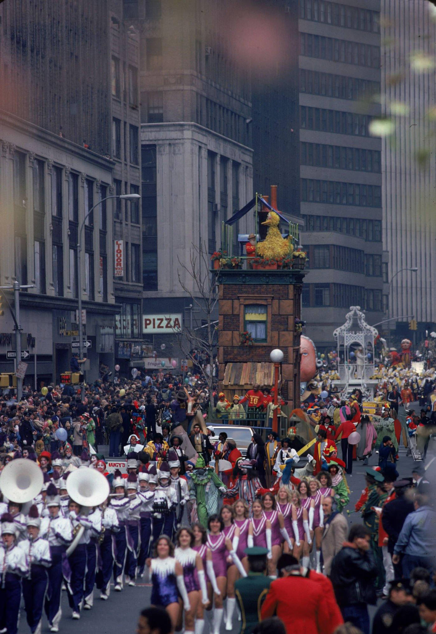 A Marching Band Is Followed By A Sesame Street Float As Crowds Look On During The Macy'S Thanksgiving Day Parade, Circa 1980.