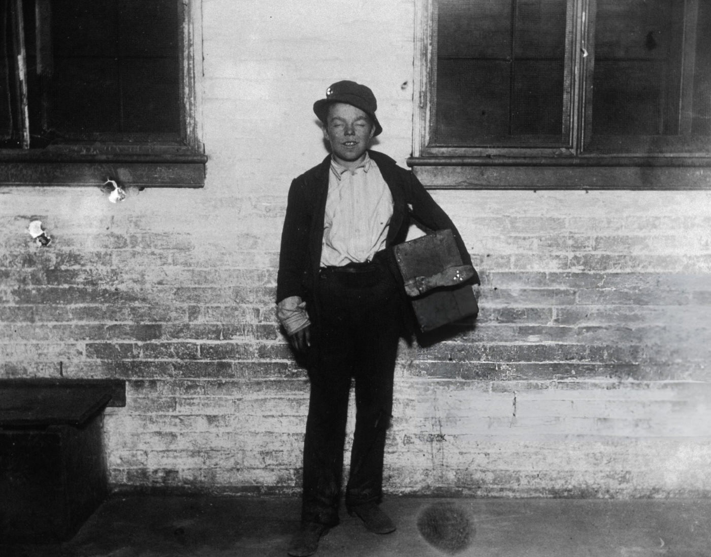 Portrait Of A Disheveled Shoeshine Boy Named Tommy, Holding A Shoeshine Kit On A Sidewalk, New York City, 1900S