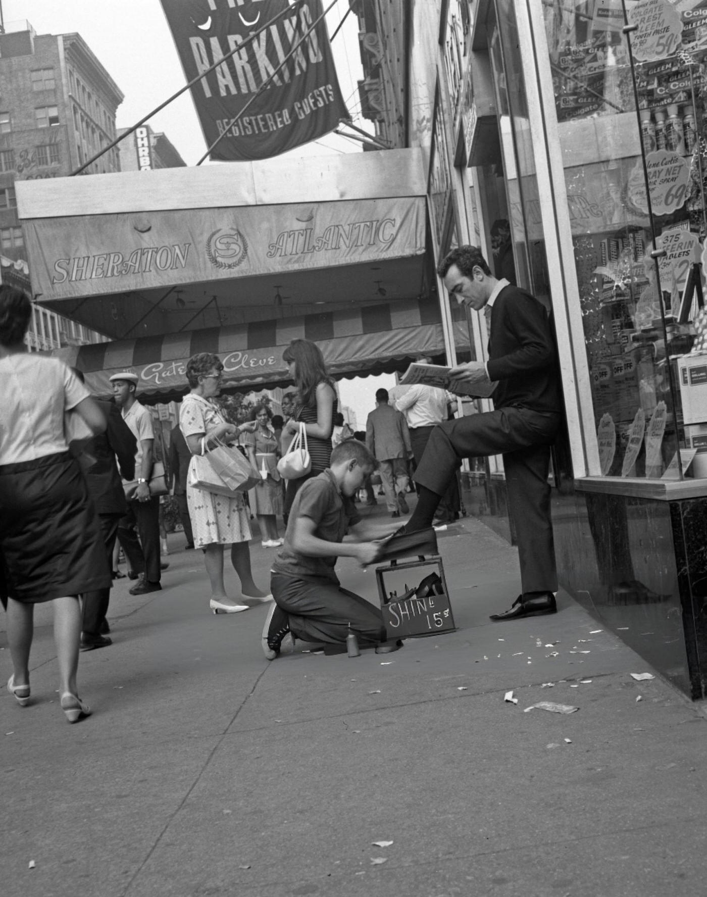 A Young Boy Shines A Man'S Shoes As He Reads The Papers On Seventh Avenue In Front Of The Sheraton Hotel In Times Square, New York, June 1, 1967.