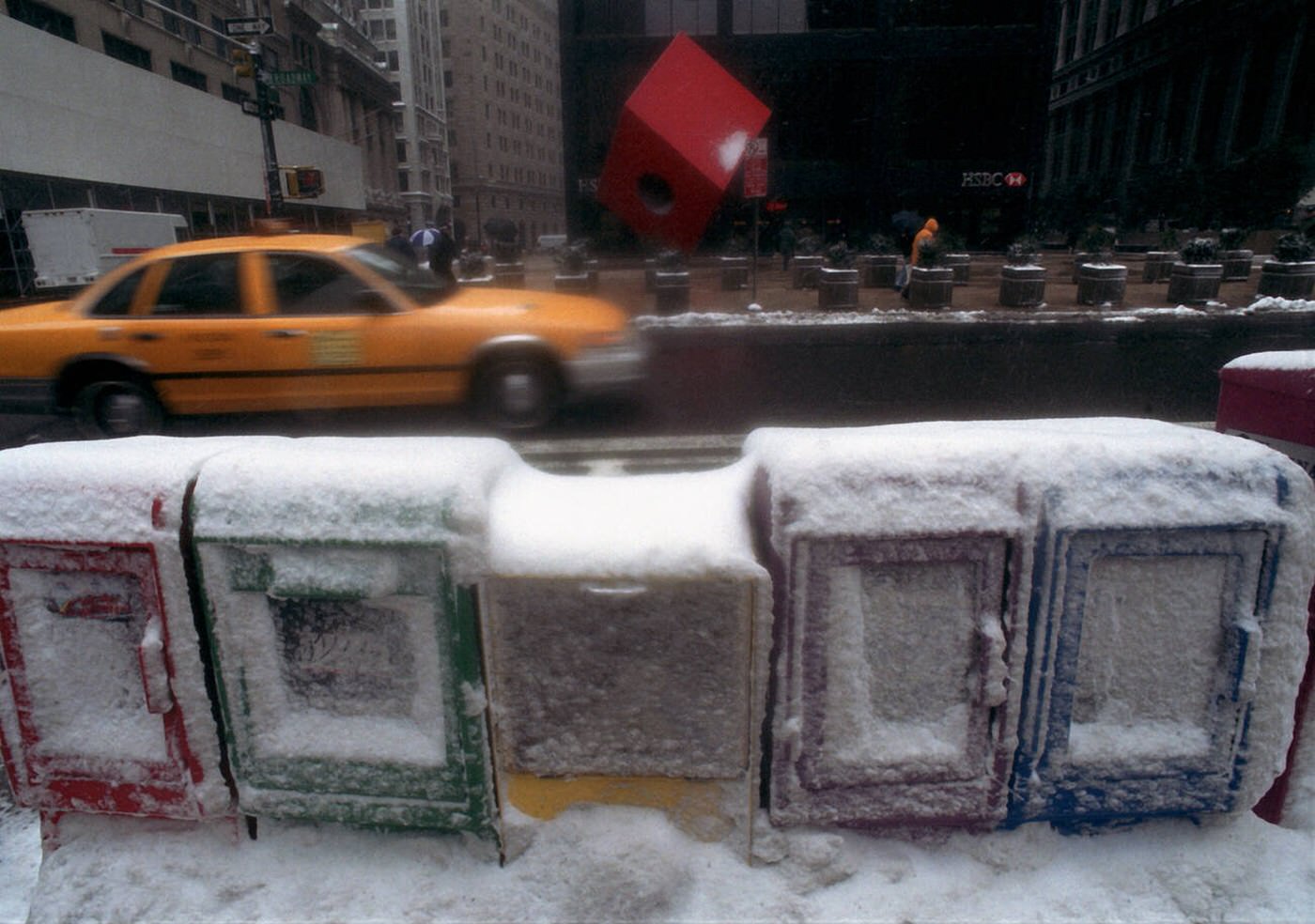 A Taxi Speeds Down Broadway Past Snow Encrusted Newspaper Boxes During A Snowstorm, 2001.