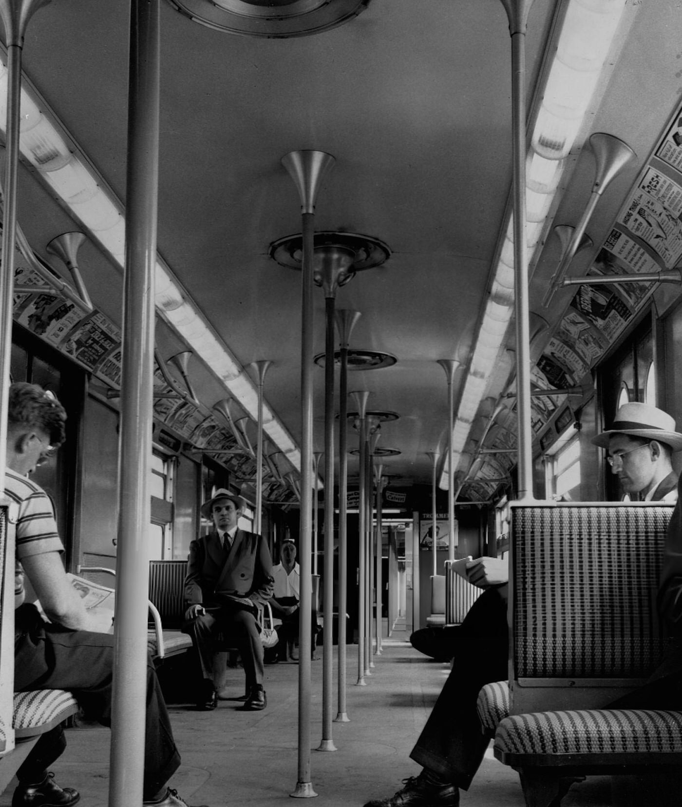 Passengers Ride On Cushioned Seats Beneath Fluorescent Lighting In A Luxury Subway Train, Circa 1950, New York City.