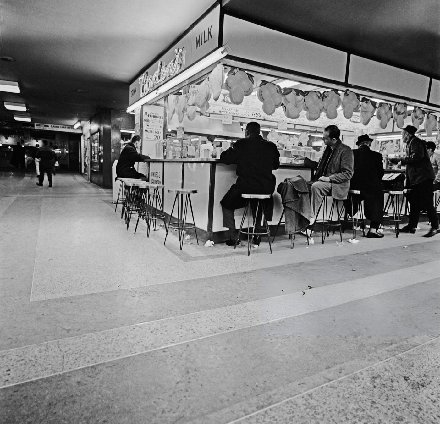People Sit On Stools Around An Unspecified Food Stand At The Times Square-42Nd Street/Port Authority Bus Terminal Subway Station In New York City, January 22, 1964.