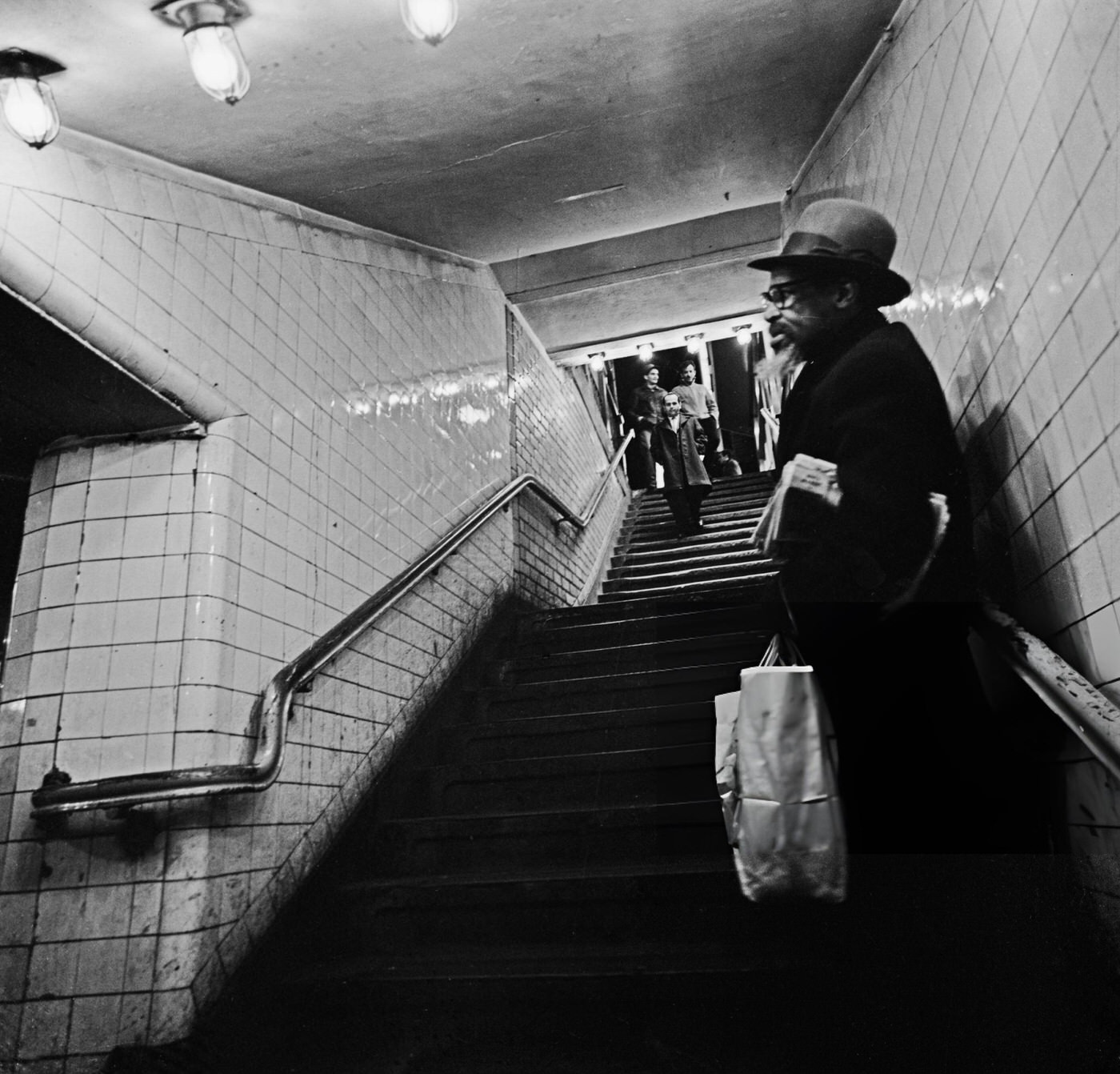 A Man Stands On The Steps With A Group Of People At The Top Of The Steps In The Background At The Times Square-42Nd Street/Port Authority Bus Terminal Subway Station, January 22, 1964.
