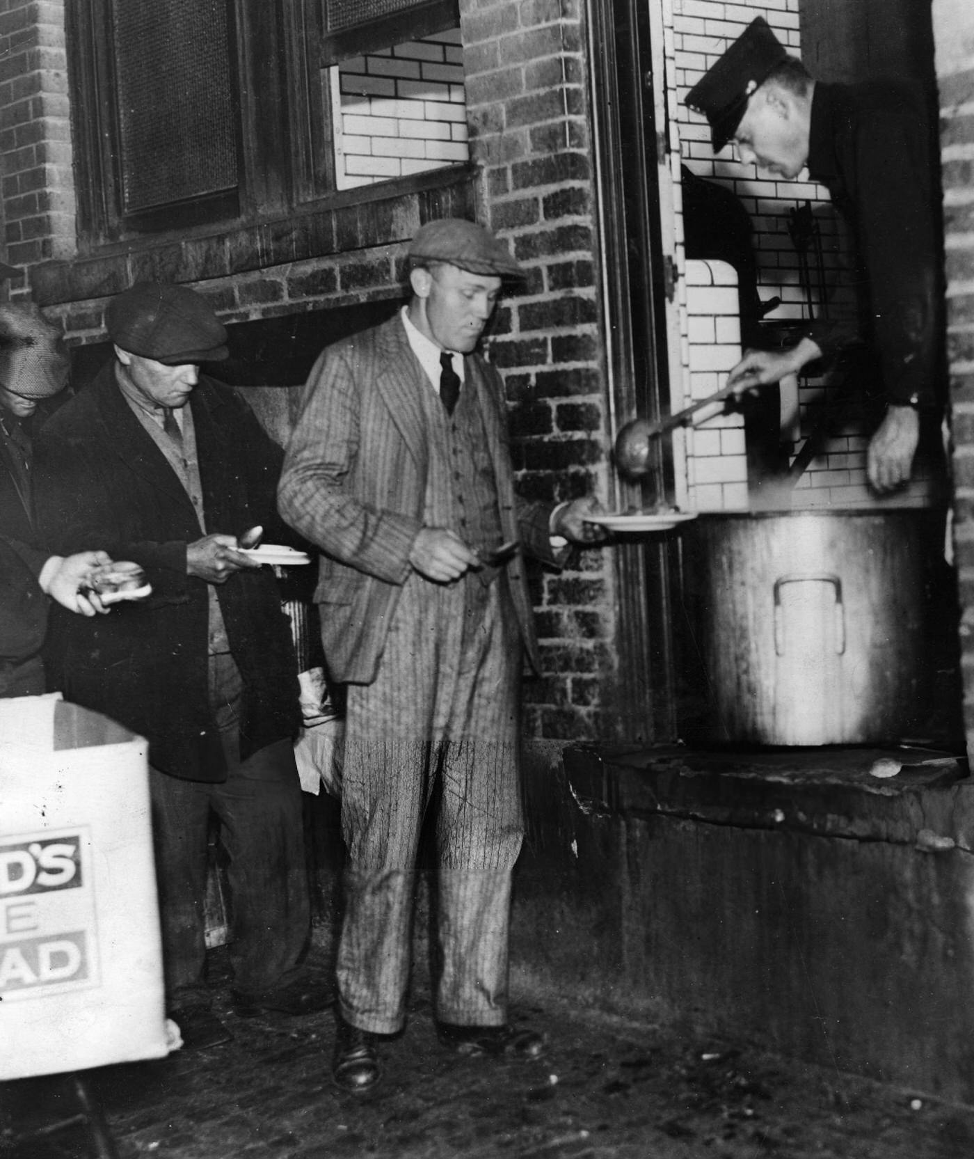 A Man Extends His Plate To Get Food From A Soup Line During The Great Depression, New York City, 1932.