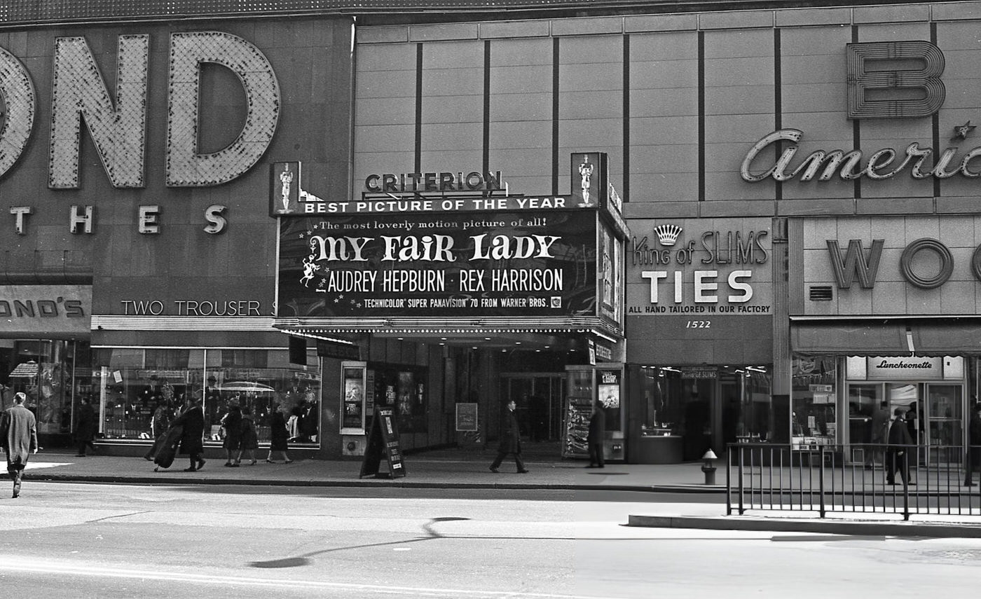 Pedestrians Walk Past The Criterion Theater On Broadway In Times Square, Where 'My Fair Lady' Is Advertised, March 1966.