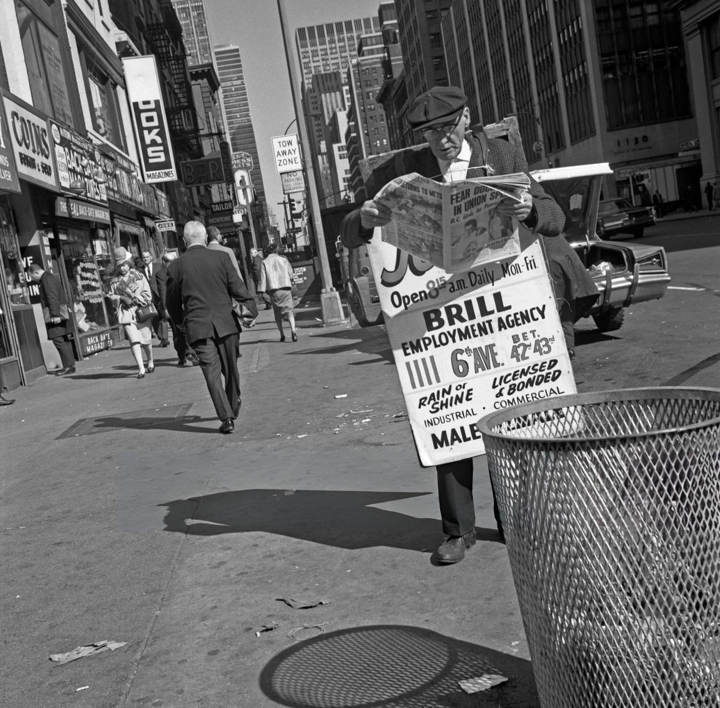 A Man Wearing A Billboard Advertisement Reads The News Paper On 42Nd Street In Times Square, June 1, 1967.
