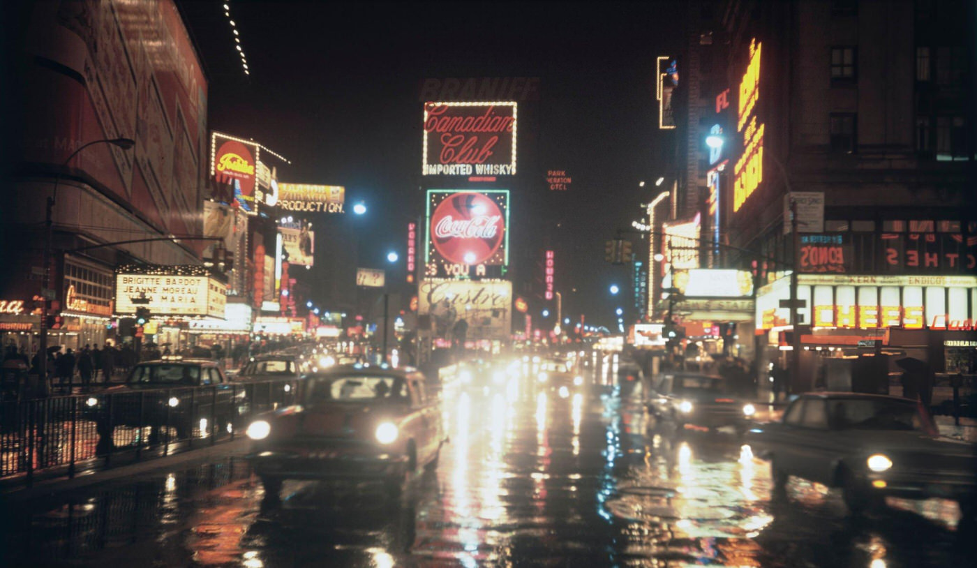 Night Time View Of Neon Signs Illuminating Times Square As Cars And Pedestrians Cross The Intersection Of Broadway And 7Th Avenue, August 1967.