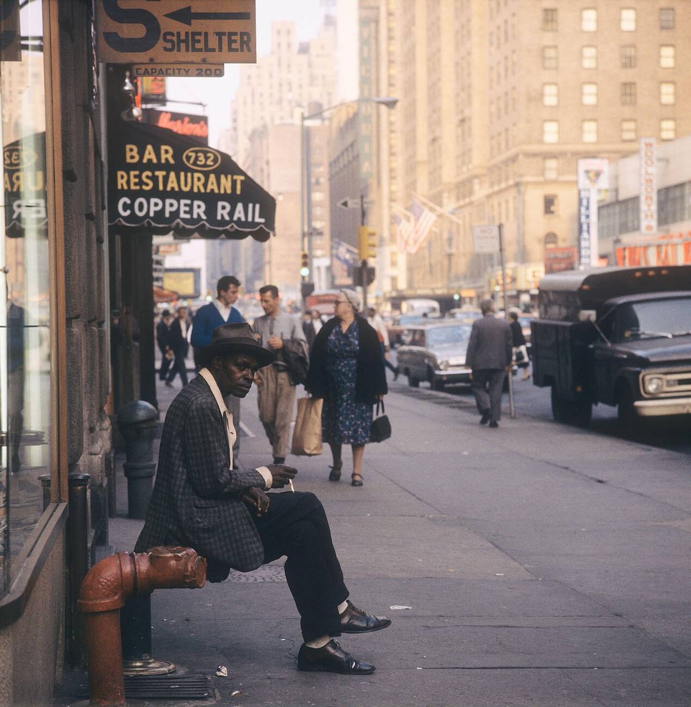 Street Scene With A Man Sitting In Front Smoking, 1964.