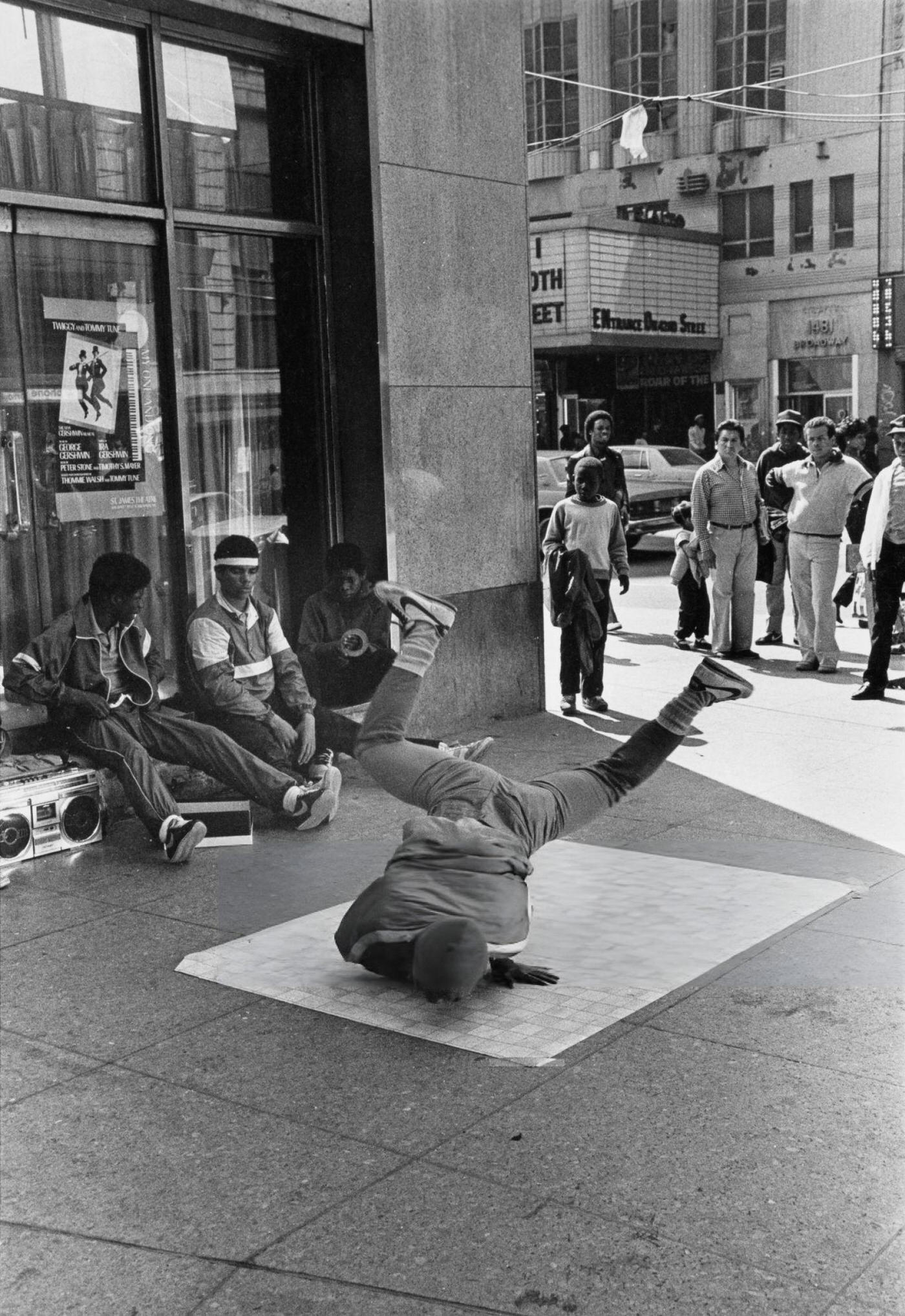 A Youth Windmills On Linoleum As Three Youths Watch With A Boombox In Times Square, Circa 1980.