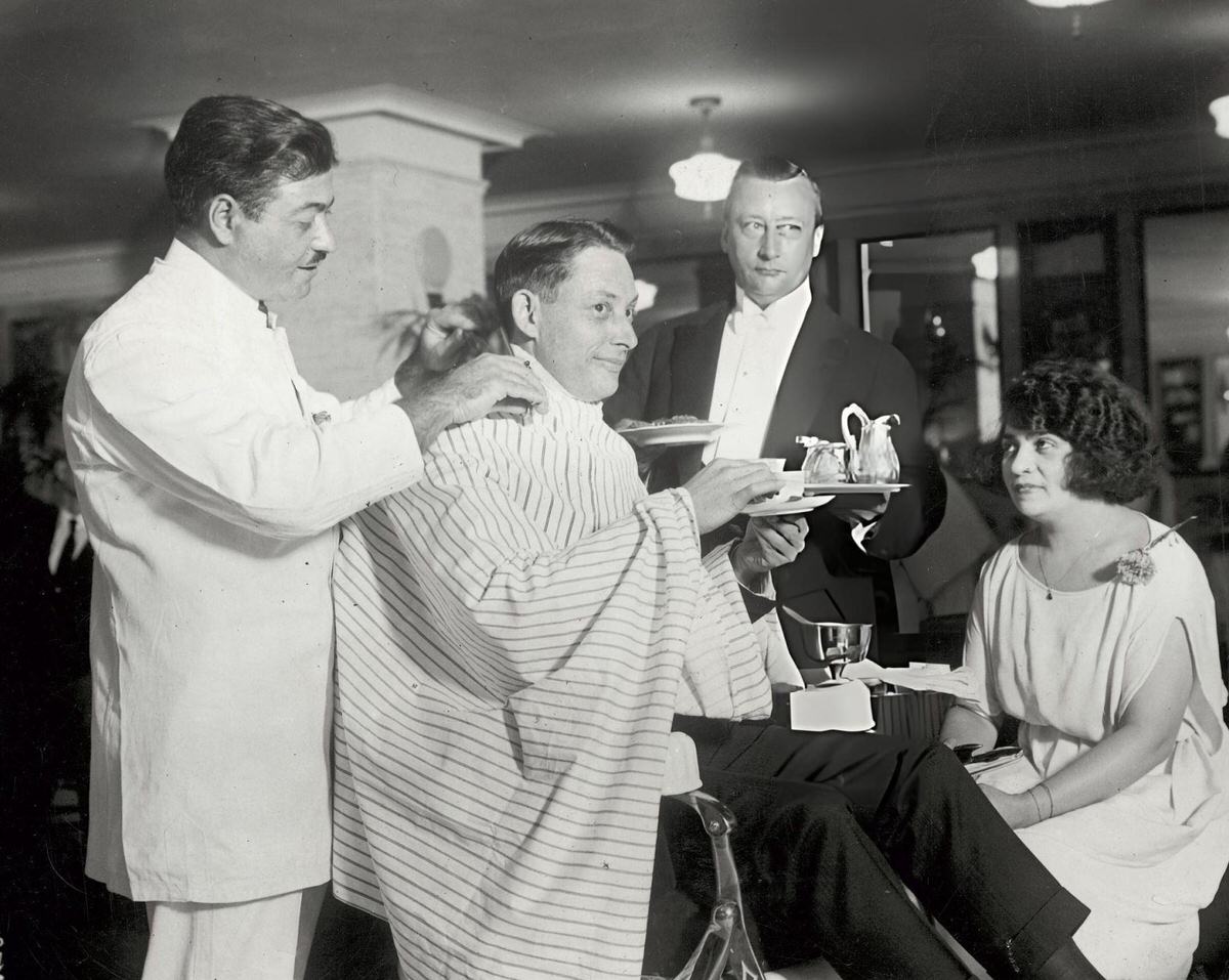 Customer Receiving A Haircut, Manicure, And Shoe Shine At The Terminal Barber Shop In The Knickerbocker Building, New York.