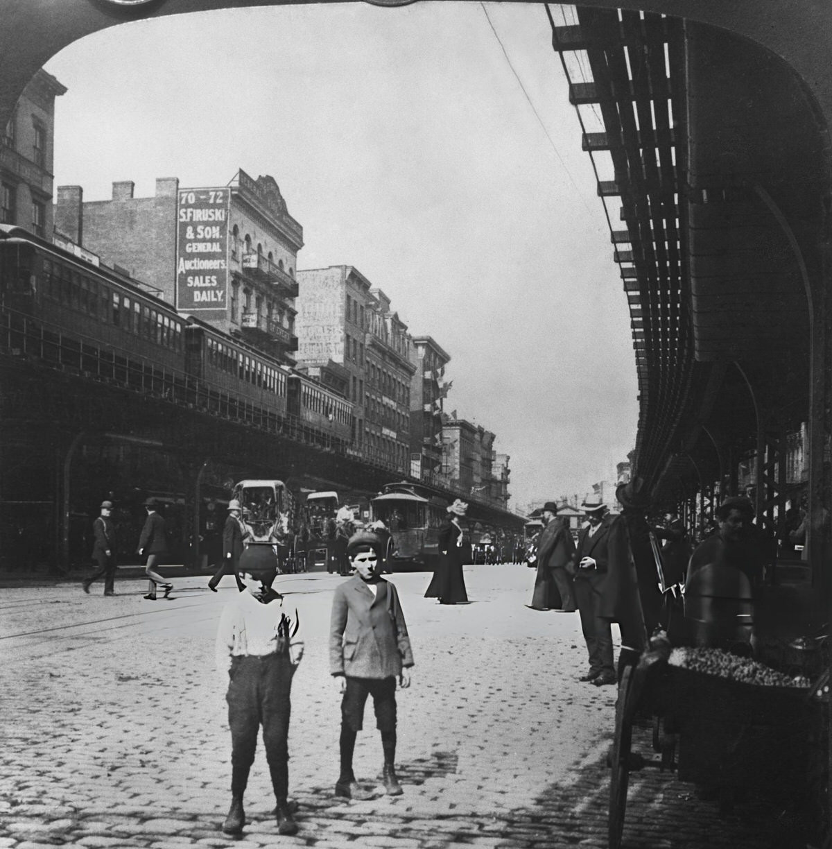 Two Young Boys On A Cobbled Road Beneath An Elevated Rail Line In The Bowery, New York, 1900.