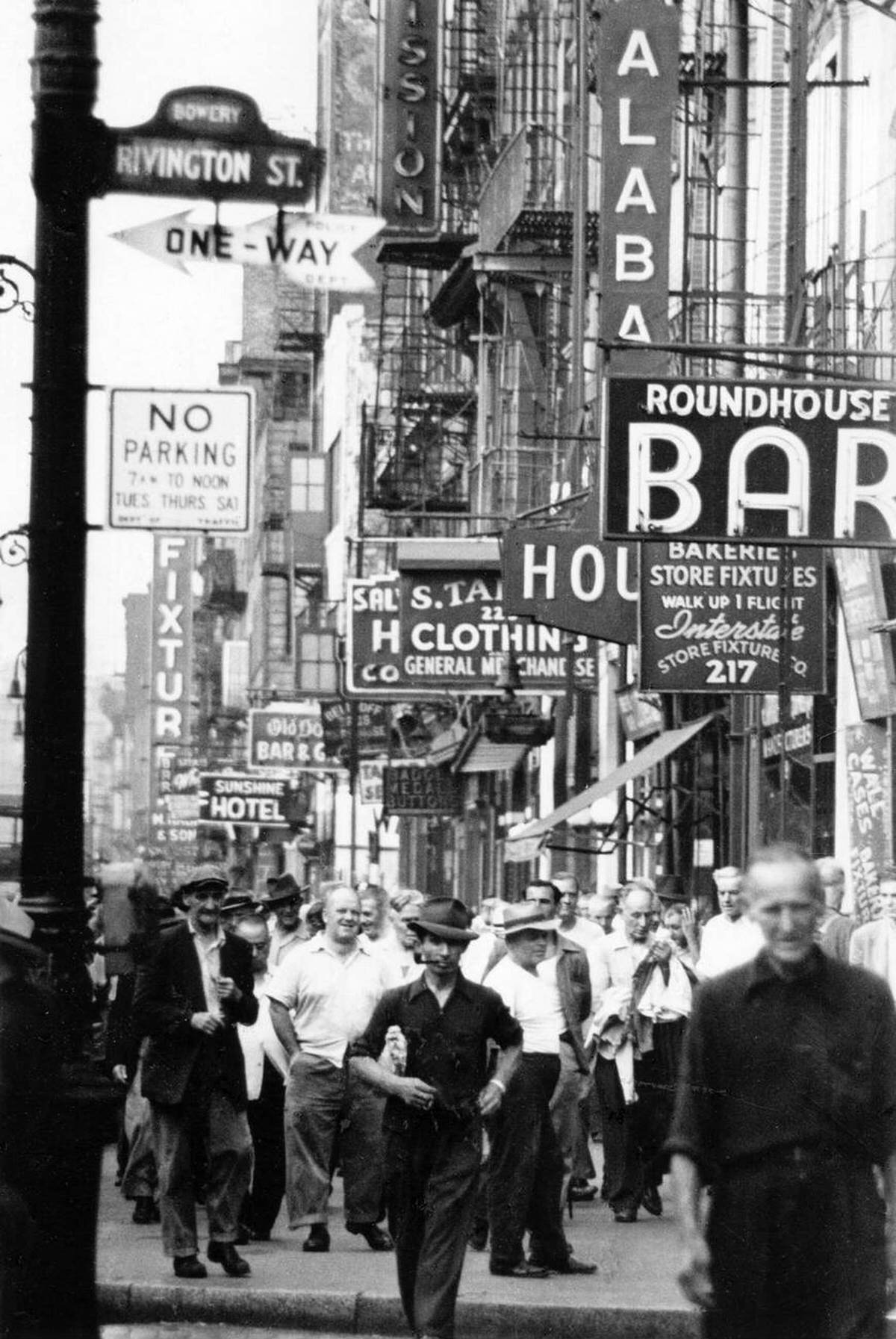 Pedestrians Walking Past The Roundhouse Bar And Sunshine Hotel At Rivington Street And Bowery, New York, 1940S.