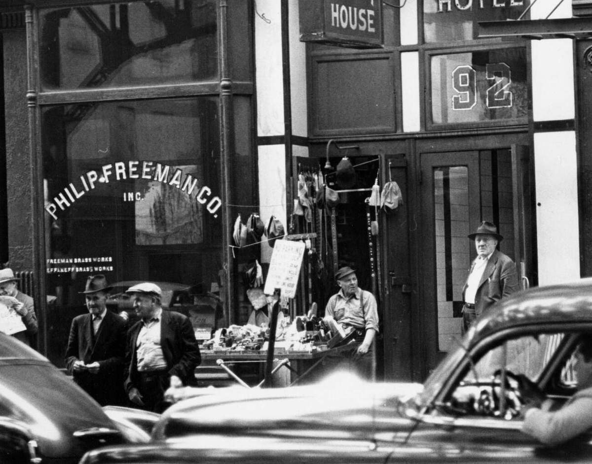 Men Gathered Outside The Philip Freeman Co. And Adjacent Shops With Classic Cars In The Foreground, New York, 1940S.