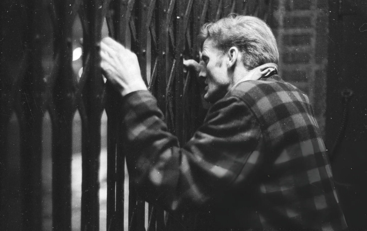 Man Peering Through Metal Gates In The Bowery, New York, 1961.