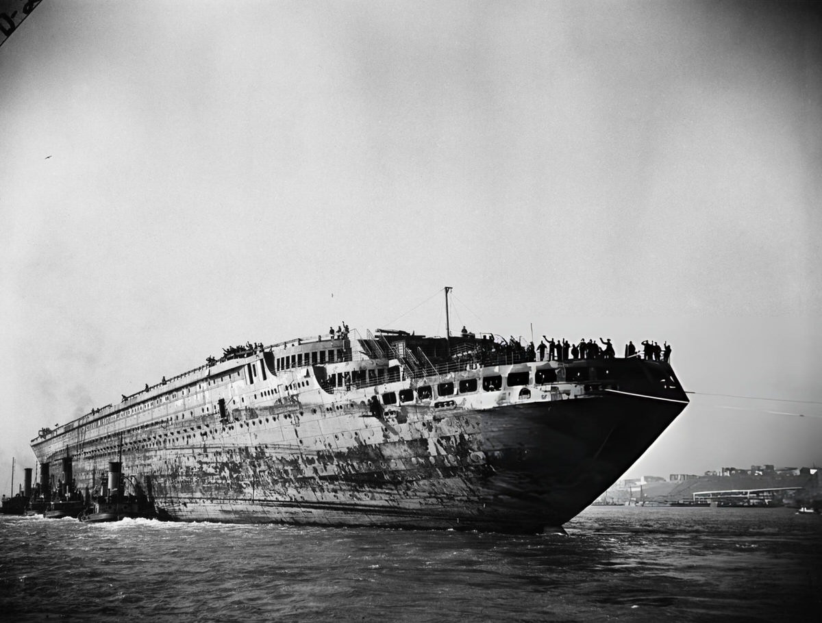Fire-Damaged Wreck Of The Ss Normandie Being Towed To The Brooklyn Navy Yard, 1943.
