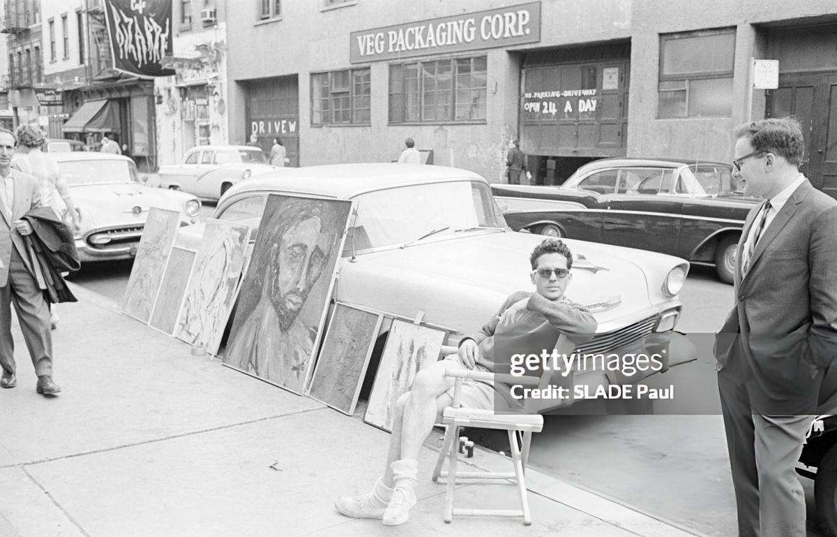 Artist Exhibiting Paintings Against A Parked Car, Greenwich Village, 1961.