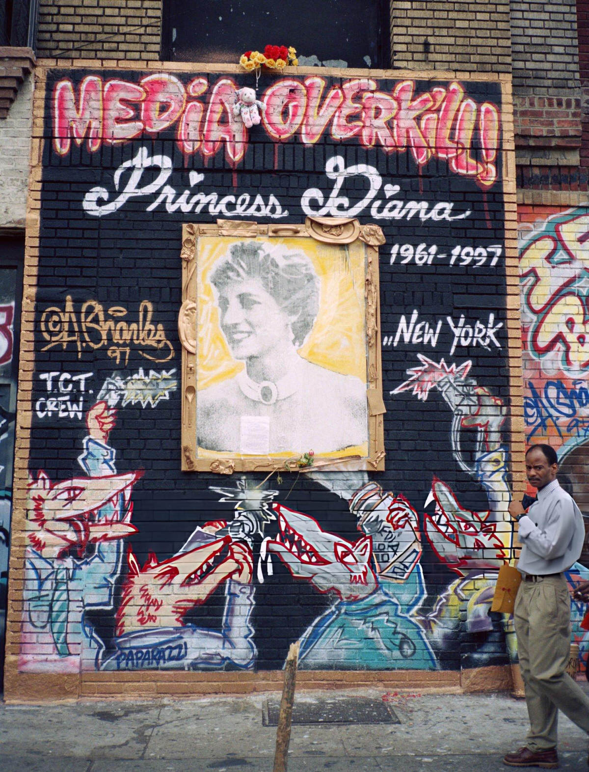 Pedestrian Walking Past A &Amp;Quot;Media Overkill!&Amp;Quot; Mural In The East Village, 1990.