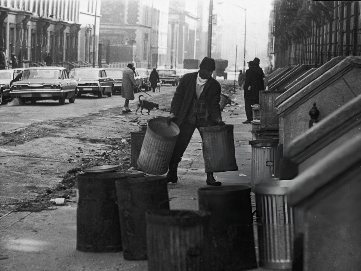 Man Carrying Metal Trash Cans Outside An Apartment Building On 114Th Street, Harlem, 1968.