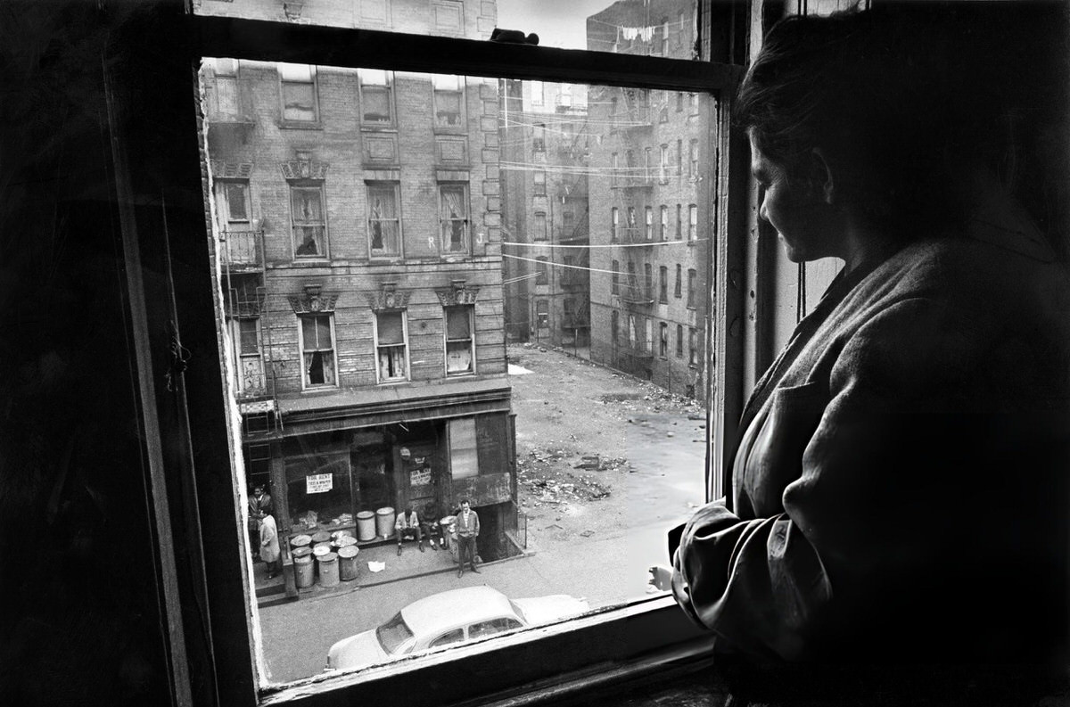 Woman Looking Out The Window Of An East Harlem Apartment.