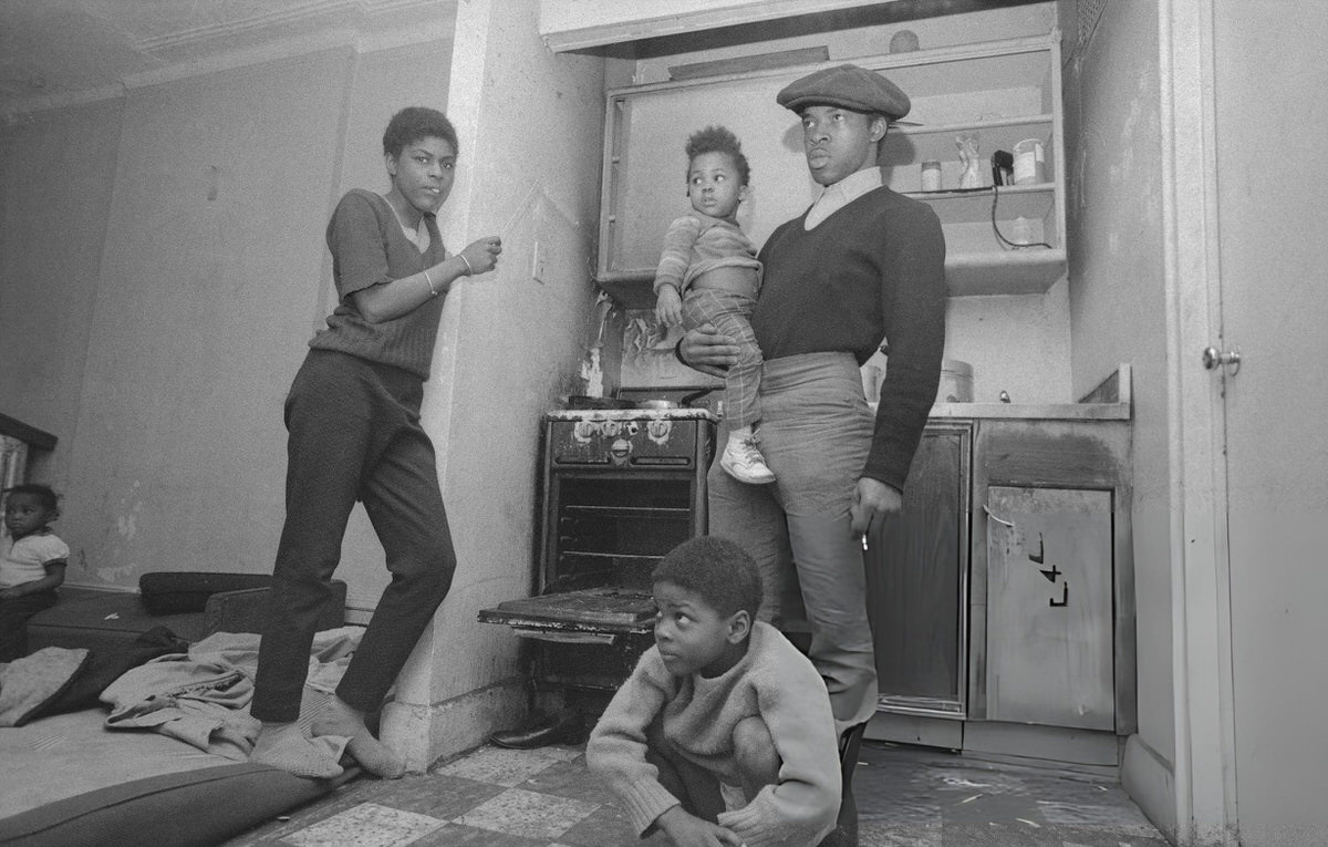 Family Standing By An Open Stove For Warmth In An East Harlem Apartment, 1970.
