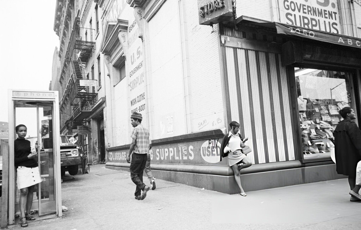 Woman In A Phone Booth Holding A Pepsi-Cola Near A Government Surplus Store, Harlem, 1970.
