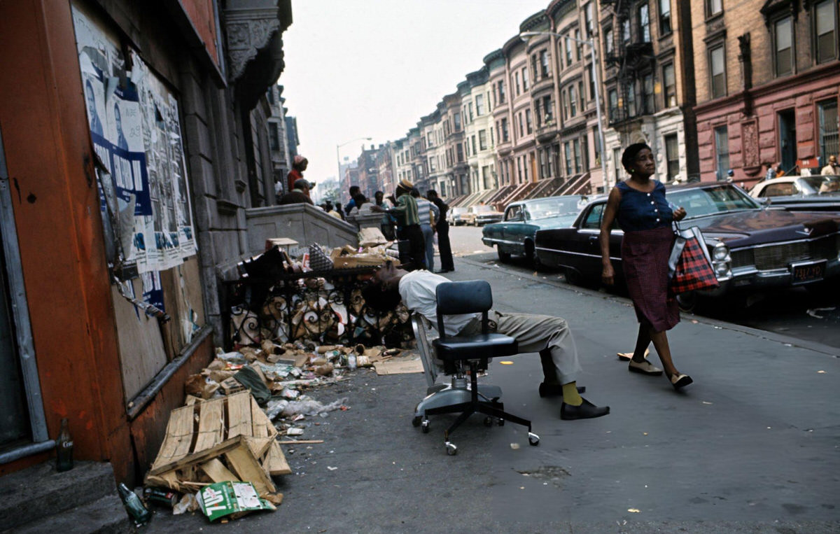 Unemployed Man Sitting In An Office Chair On A Harlem Street Near Debris, 1970.
