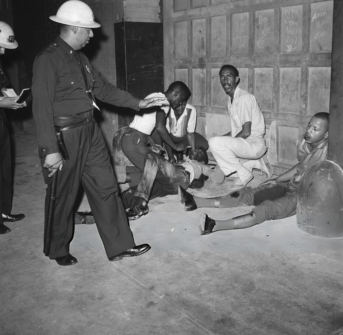 Police Officer Guarding Injured Protesters During The Harlem Riots, 1964.