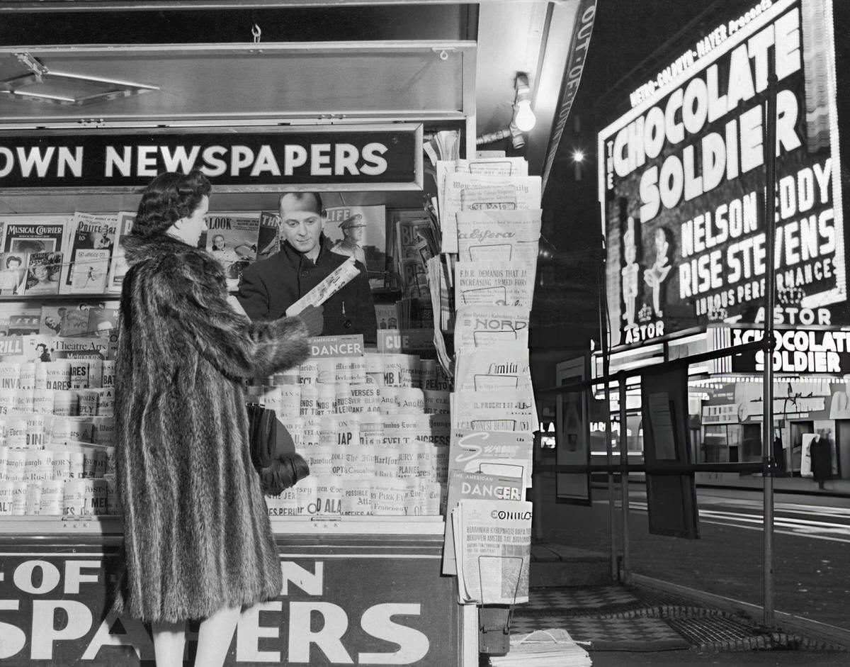 Woman In A Fur Coat Purchasing A Paper At An Out-Of-Town Newsstand In Times Square, New York, 1941.