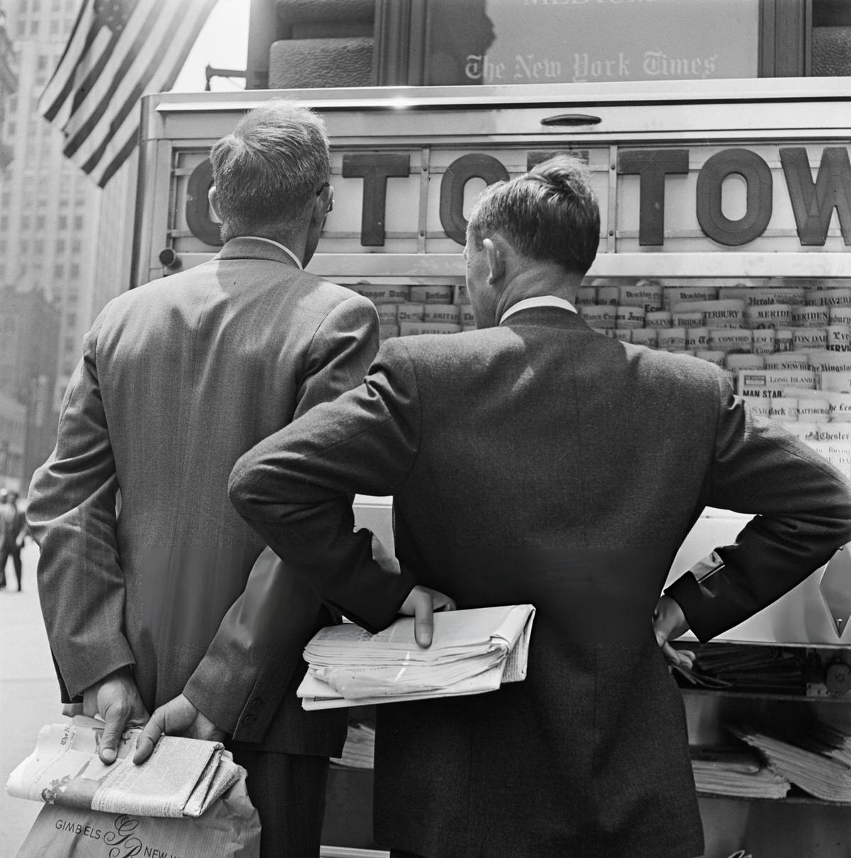 Men Inspecting Newspapers At A Stand, New York, 1950.