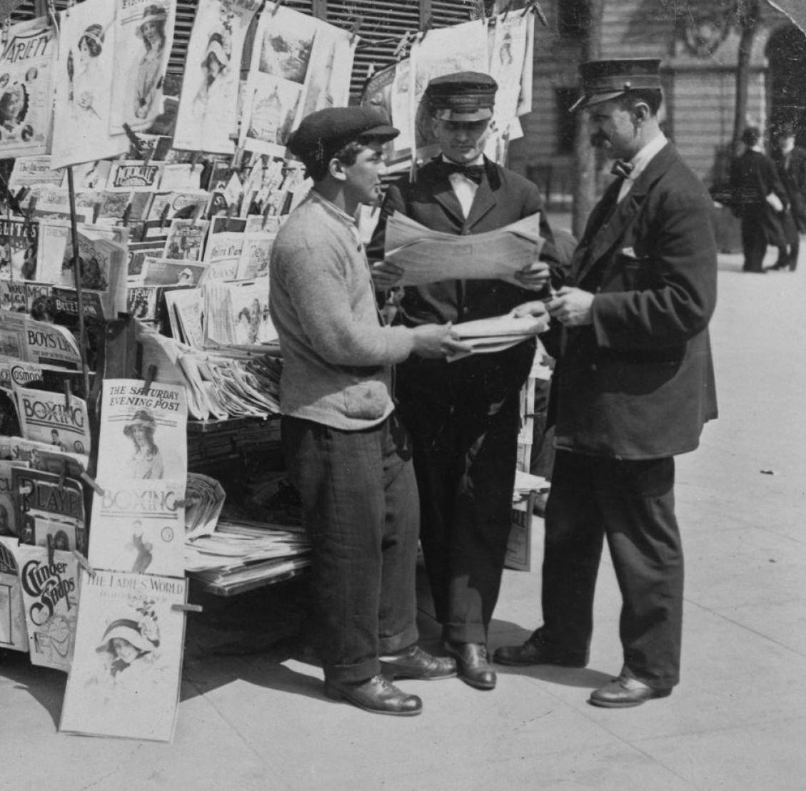 Men In Towerman Uniforms Standing By A Newsstand In City Hall Park, Manhattan, 1900.