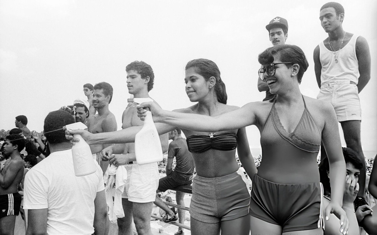 Two Women Using Spray Bottles To Splash Passersby On The Boardwalk At Orchard Beach, Bronx, 1984.