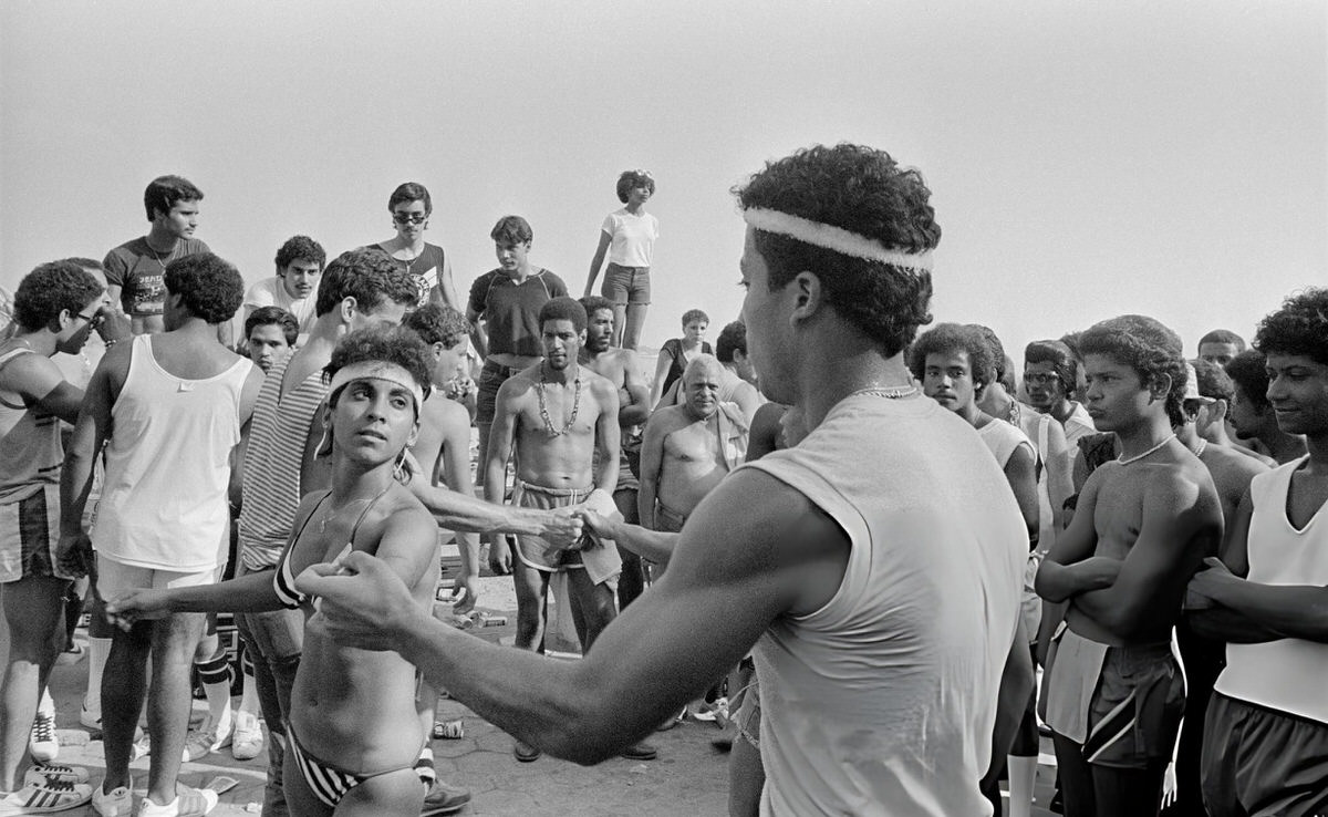 Couple Dancing On The Boardwalk As A Crowd Looks On At Orchard Beach, Bronx, 1983.