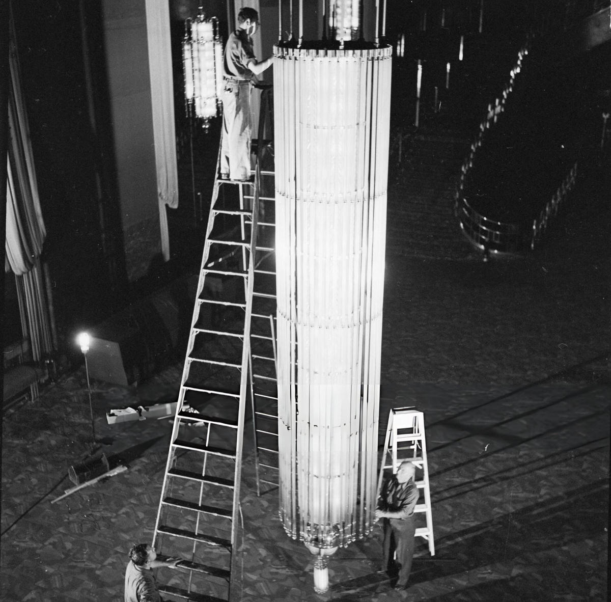 Stagehands Erecting An Art Deco Chandelier Over The Grand Staircase At Radio City Music Hall, New York, 1950.