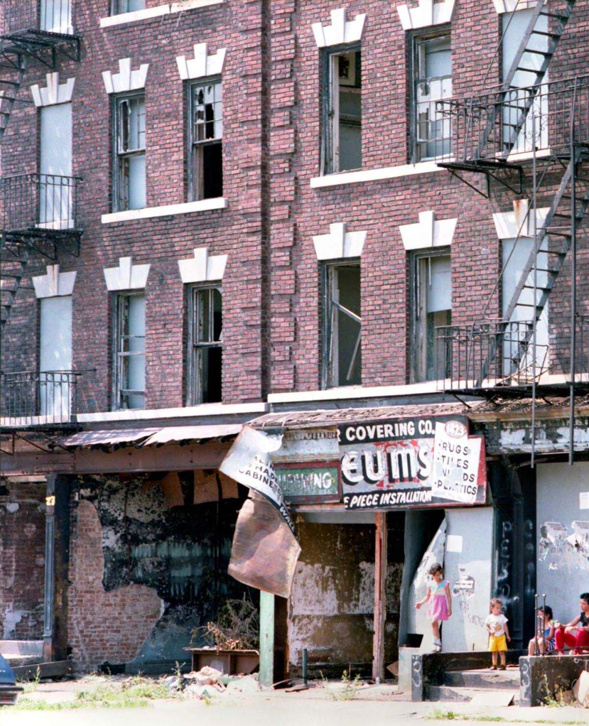Woman And Three Children On The Stoop Of A Fire-Damaged Tenement Building, South Bronx, 1980.