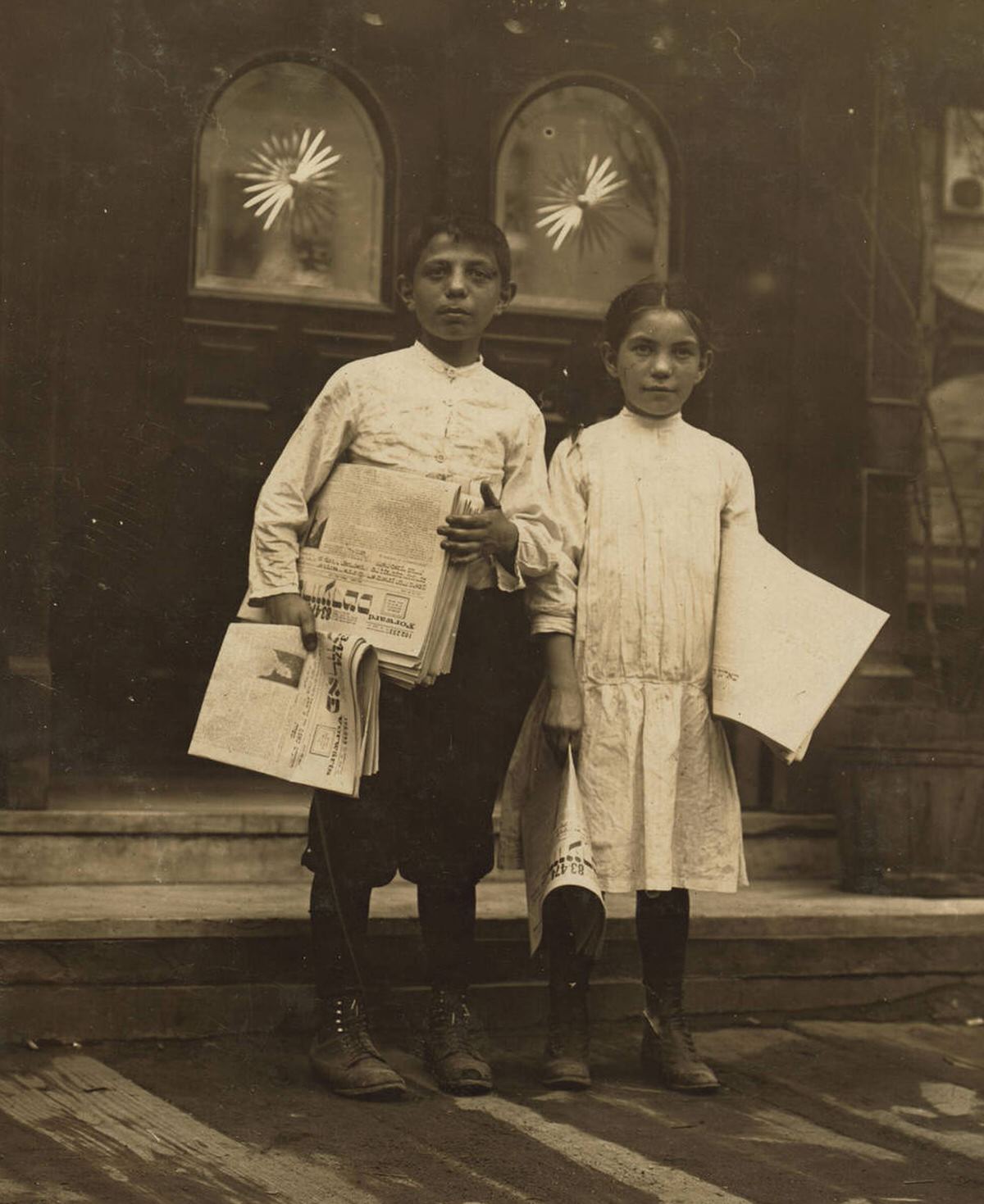 Newsgirl And Newsboy Selling Papers Near Saloon Entrances In The Bowery, New York.