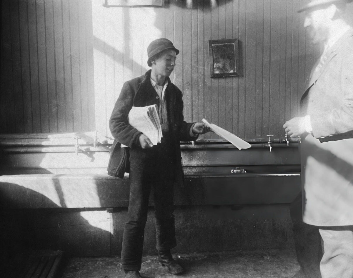 Newsboy Handing A Newspaper To A Man In A Restroom At The Duane Street Lodging House, New York, 1905.