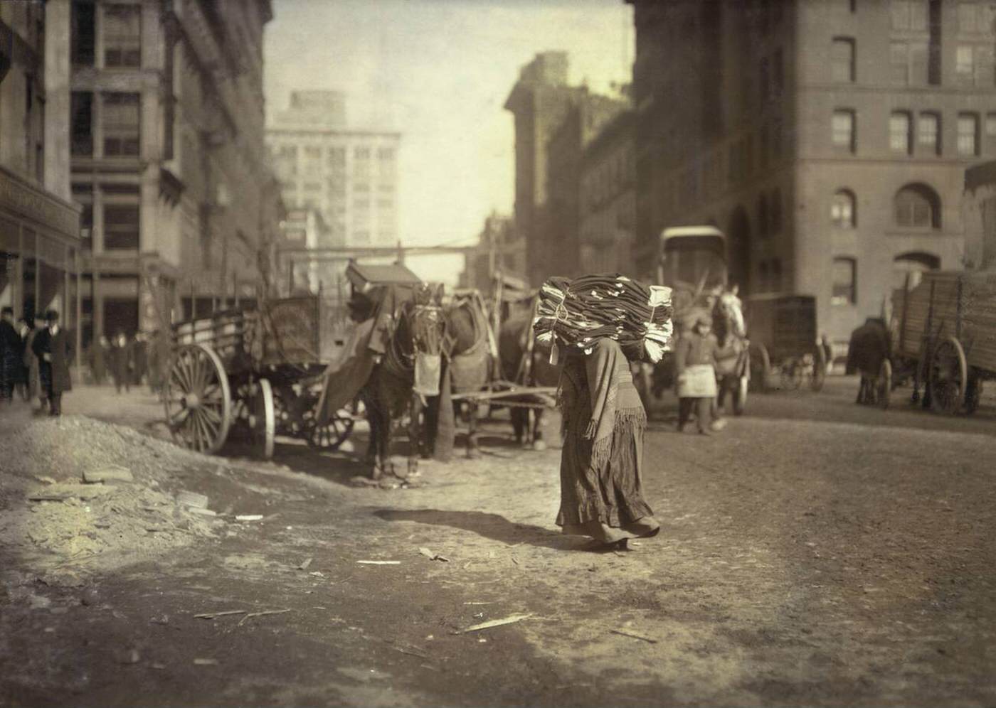 Woman Carrying A Heavy Load Of Clothes On Lafayette Street, New York City, 1912