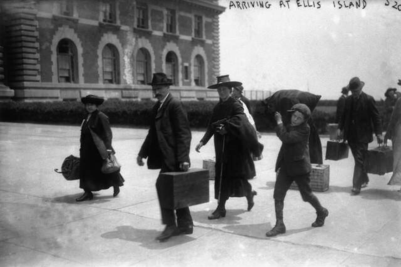 Immigrants Carrying Luggage Arriving At The Ellis Island Immigration Center, 1900