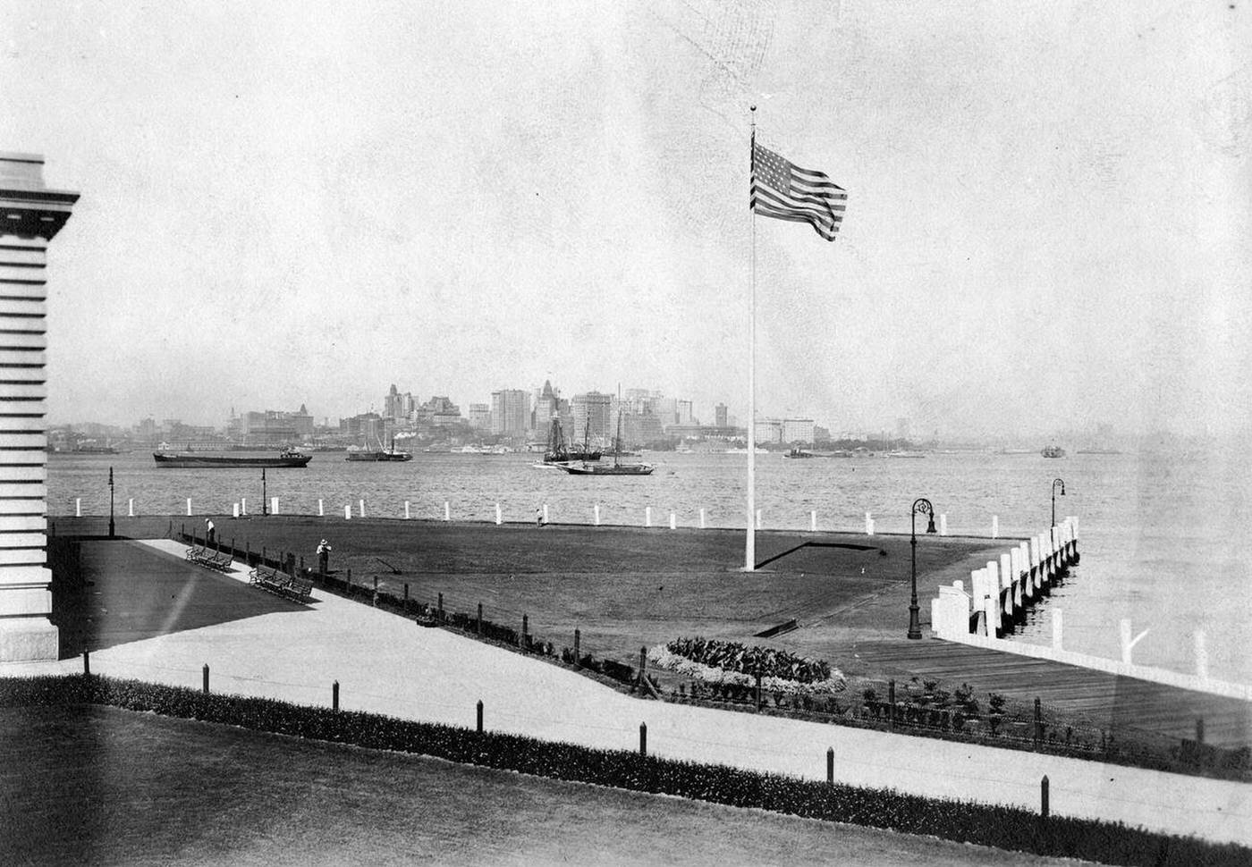 Lawn Surrounding The Immigration Inspection Station On Ellis Island With The Manhattan Skyline In The Background, 1907